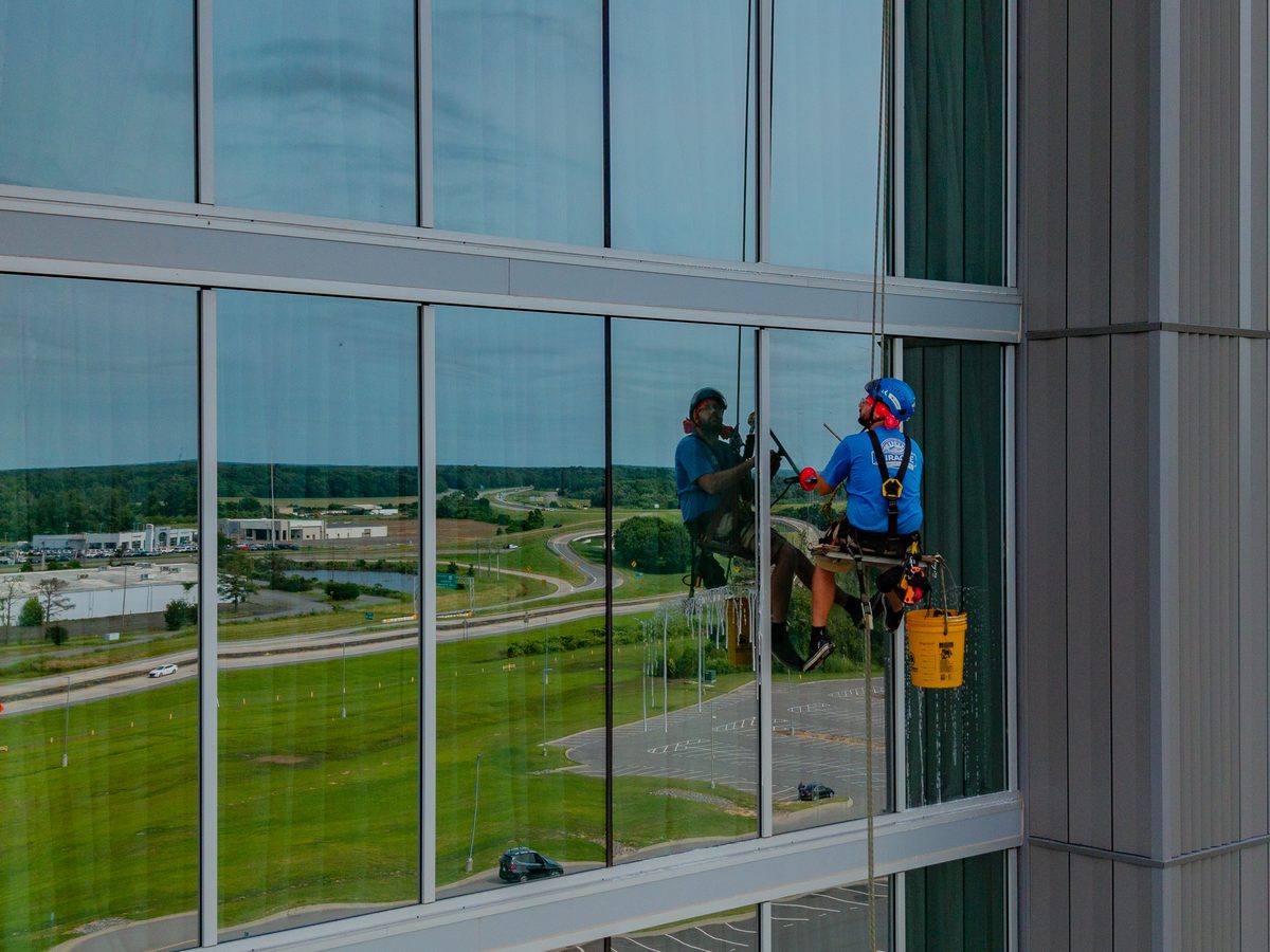 Miracle technician doing commercial window cleaning on a glass facade from rope access lines in Central Arkansas