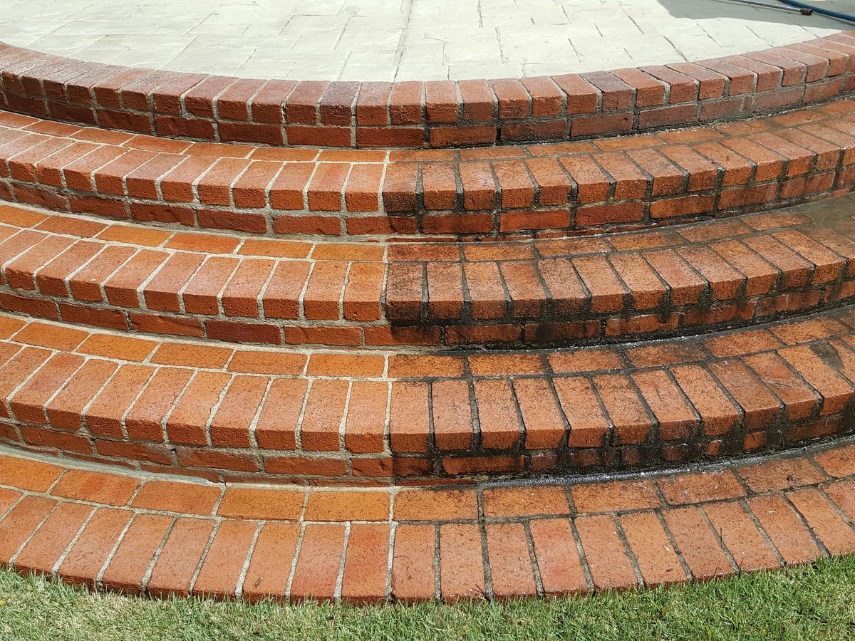 Brick entry steps in Little Rock Arkansas part way through a pressure wash, cleaned brick beside untreated