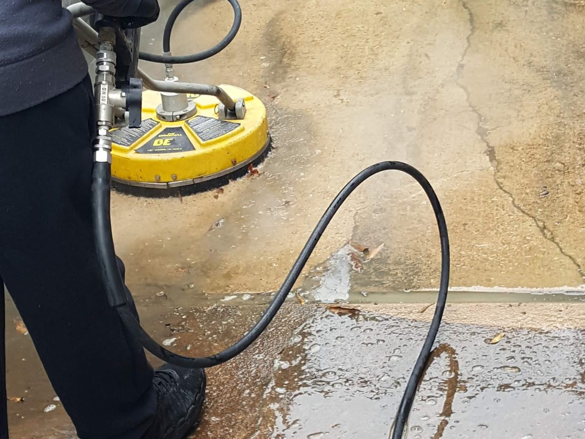 Surface cleaner pressure washing a concrete walkway in Little Rock Arkansas, clean strip beside dirty concrete